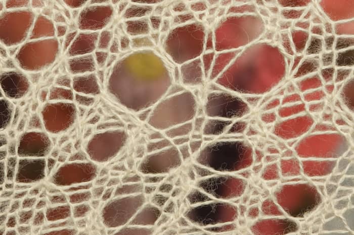 detail of artwork showing lace on red and maroon felted wool by Eve Jacobs-Carnahan