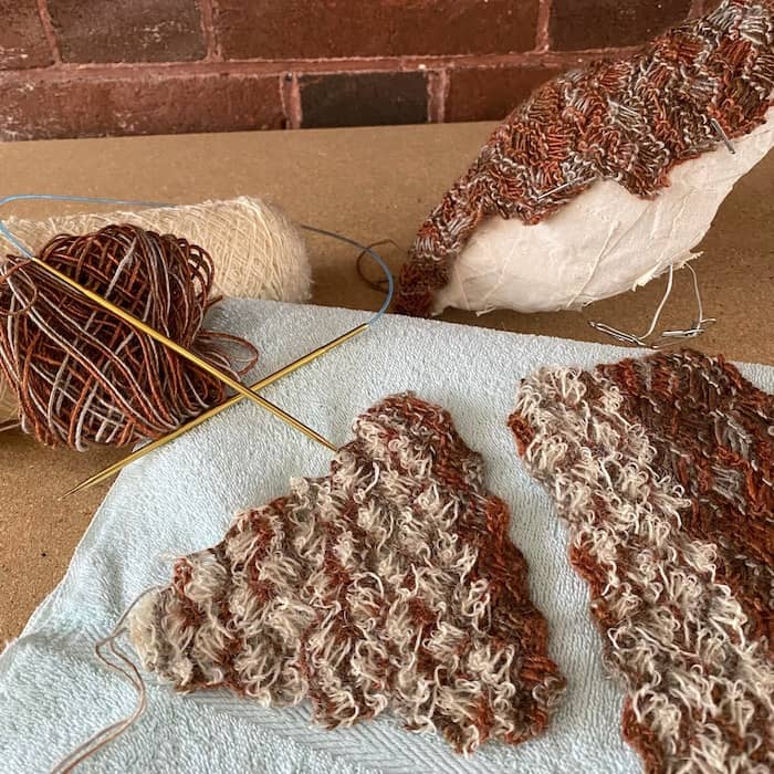 variegated brown wool and white boucle yarns knitted in loose woven cables for chicken feathers 