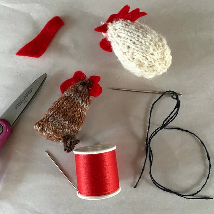 2 inch tall brown and white knitted hens with red thread and scissors in studio of Eve Jacobs-Carnahan