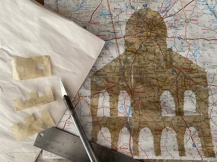 mulberry paper cut out of state capitol with ruler and x-acto knife against map of Georgia