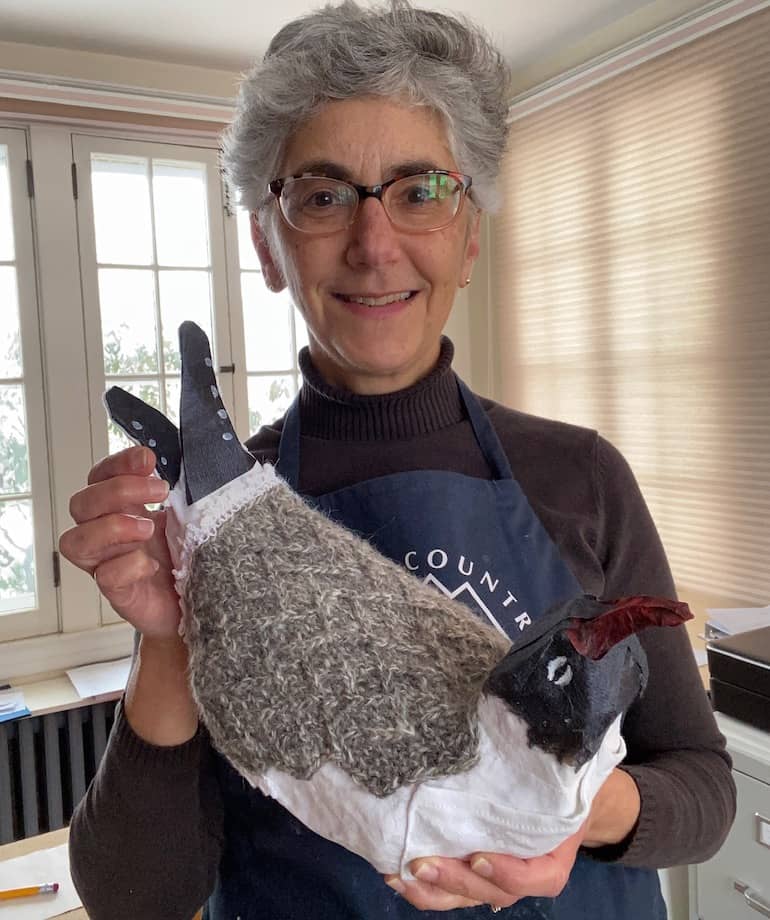 woman holding mixed media gull with black head and tail, white underbody, and grey knitted back and wings