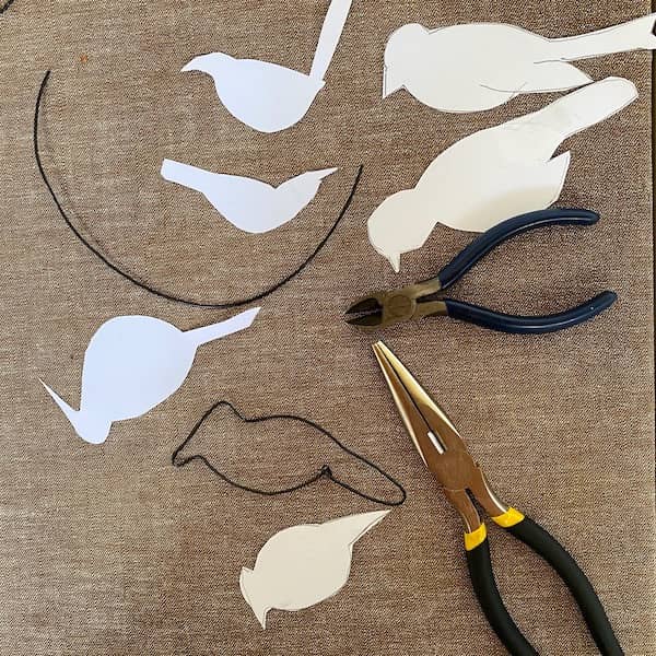 paper templates of bird shapes with wire, pliers, and bent wire bird outline