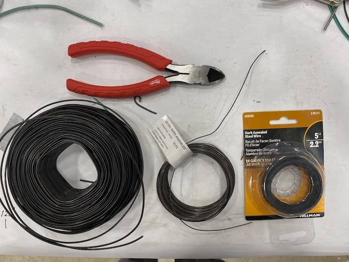 rolls of steel wire in different gauges with wire cutter on workbench