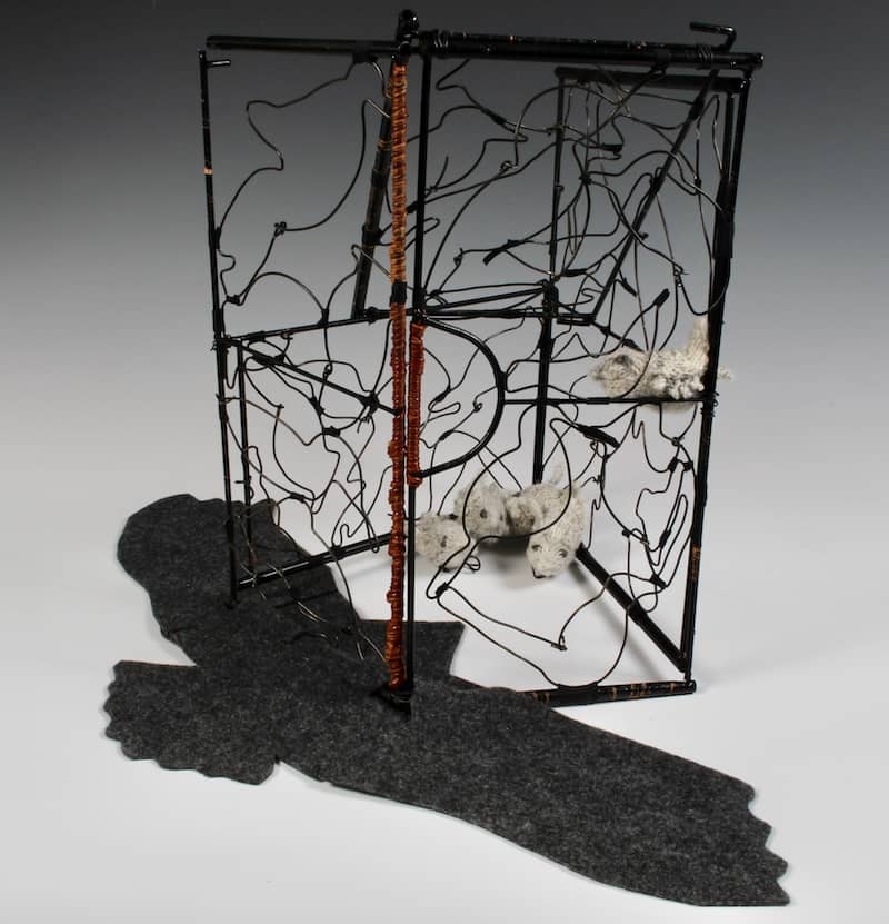 sculpture with black shadow of bird with outstretched wings, wire cage structure adorned with bird shapes, tiny knitted birds in corner