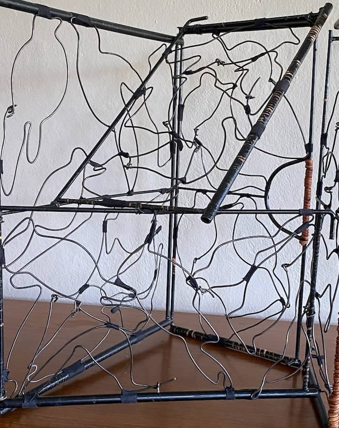 black steel wire silhouettes of birds attached to steel frame rectangles leaning on each other