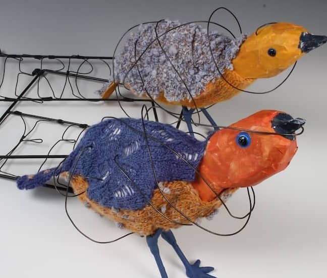 blue violet and yellow orange bird sculptures with swirling black wire loosely wrapped around and attached to their bodies